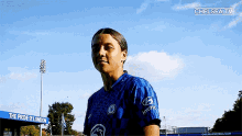 a woman wearing a blue hyundai jersey is standing in front of a blue sign that says the pride of london .