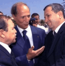 three men in suits are talking to each other