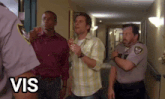 a group of men are walking down a hallway and the word vis is on the bottom right