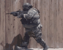 a soldier is running with a gun in his hand .