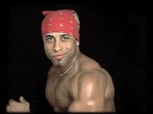 a shirtless man wearing a red bandana on his head is standing in front of a black background .