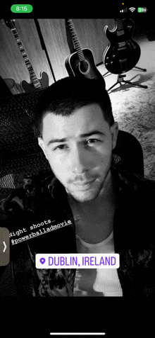 a black and white photo of a man with guitars behind him