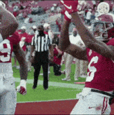 a football player with the number 3 on his jersey is raising his arms in the air while a referee stands behind him .