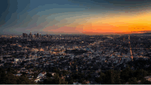 an aerial view of a city at sunset with a city skyline in the background