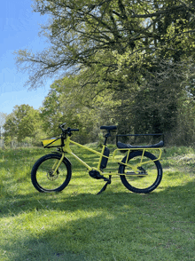 a yellow bicycle with a basket on the front is parked in a grassy field