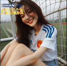 a girl wearing a manchester united jersey sits on a soccer goal