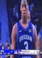 a brigham basketball player stands in front of a scoreboard