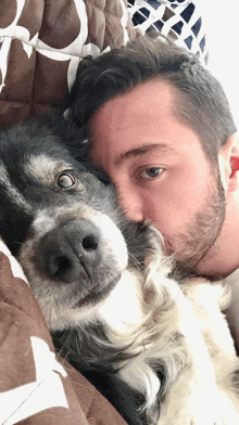 a man laying on a bed with a dog on his chest