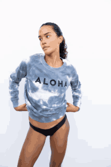 a woman wearing a blue tie dye sweater that says aloha