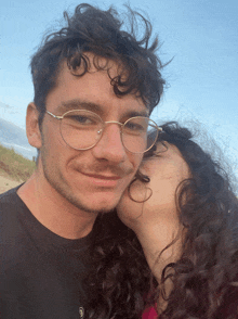 a woman kisses a man on the cheek while he wears glasses