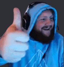 a man with a beard and headphones is giving a thumbs up .