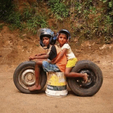 a boy and a girl are riding a motorcycle made out of old tires and barrels .