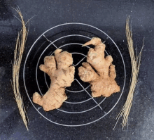 two ginger roots are sitting on a cooling rack on a black surface .