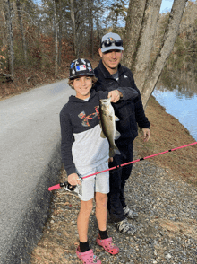 a boy wearing an under armour shirt holds a fish