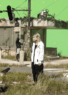 a man in a white jacket stands in front of a green screen with the letter l on it