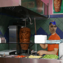 a man wearing a blue hat that says ' kebab ' on it is preparing food