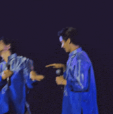 a man in a blue shirt is holding a microphone in his hand