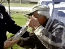 a man in a hat is drinking from a bottle while a police officer takes his blood alcohol level .