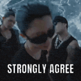 a man wearing sunglasses and a black shirt is standing in front of a group of men and says `` strongly agree '' .