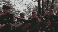 a group of men in military uniforms are sitting in a field