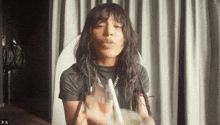 a woman with long hair is blowing a kiss while holding a straw in her hand .