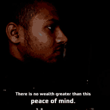 a man in a dark room with the words " there is no wealth greater than this peace of mind "