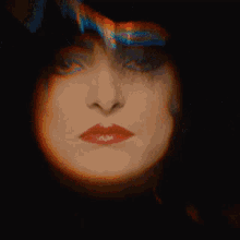 a close up of a woman 's face with a rainbow of colors behind her