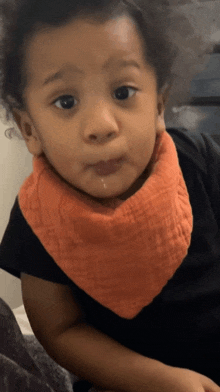 a baby wearing an orange bib is making a face