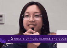 a woman wearing glasses is smiling in front of a sign that says " 6 onsite offices across the globe "