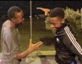 a boy wearing a black adidas jacket is standing next to another boy
