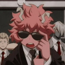 a man in a suit and tie is talking on a cell phone while wearing sunglasses .