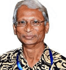 a man wearing glasses and a lanyard is smiling for the camera .