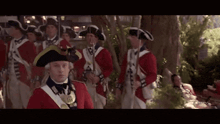a group of soldiers in red uniforms and hats are standing in a line .