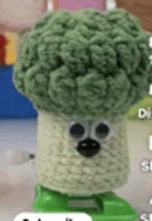 a close up of a crocheted broccoli with googly eyes and feet .