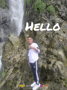 a man is standing in front of a waterfall with the word hello written on the rocks