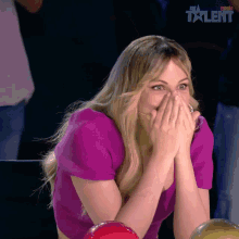 a woman in a purple top is covering her mouth with her hands in front of a sign that says spain talent