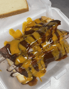 a styrofoam container holds a sandwich with ribs and cheese