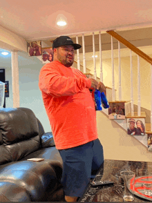 a man wearing a red shirt and a black hat is standing in a living room