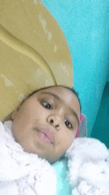 a young girl is laying on a bed with a yellow blanket on her head