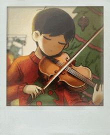 a young boy in a red sweater is playing a violin in front of a christmas tree .