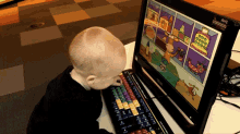 a baby is looking at a computer screen that has a cartoon on it