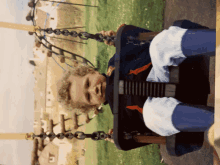 a young boy is sitting on a swing with a fish on the front of his shirt