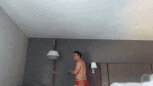 a man without a shirt is standing in a bedroom