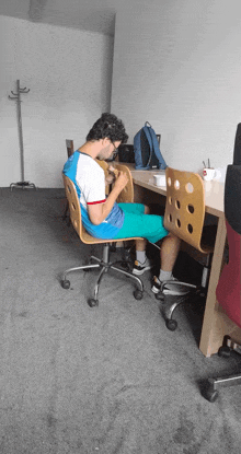 a man sits at a desk with his legs crossed and a backpack behind him