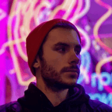 a man wearing a red beanie is standing in front of a coca cola sign