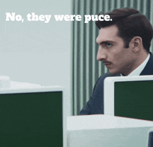 a man sitting in front of a computer with the words no they were puce behind him
