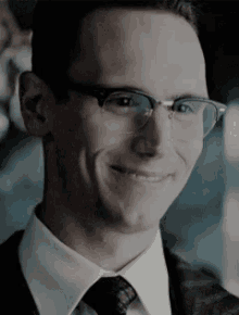 a close up of a man wearing glasses and a suit and tie .