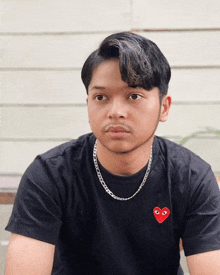 a man wearing a black t-shirt with a red heart on it