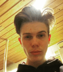 a young man is taking a selfie with a wooden ceiling in the background