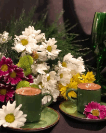 two green cups of coffee sit on green saucers with flowers in the background